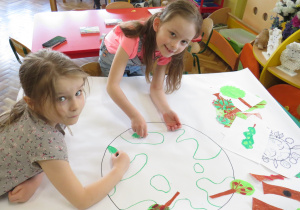 Dziewczynki z grupy Słoneczka w trakcie przygotowywania plakatu.